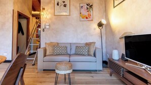 A living room with a sofa, a TV, a lamp, and a staircase. - THE LOFT by Design Studio (Bellano)