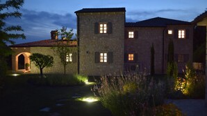 Ein Steinhaus mit zahlreichen Fenstern und einem gut beleuchteten Gartenweg.