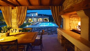Eine Terrasse im Freien mit Pool, Steinmauern und einer Essecke mit Stühlen und Tisch.