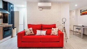 A modern living room with a red sofa, a tripod, and a dining area. - FLAT CENTER VIALIA STATIONS (MÁLAGA)