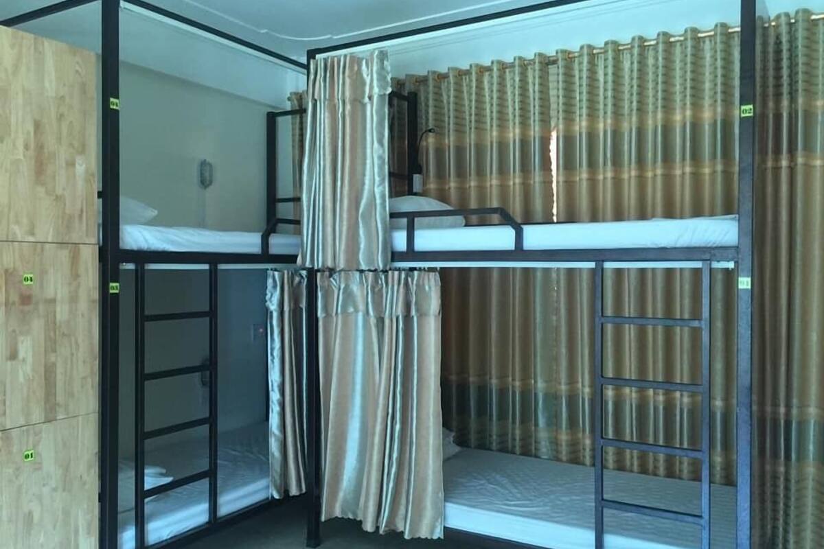 Ein Eckzimmer mit Etagenbetten, einem Holzschrank und einem Vorhang.