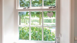 A room with a large window divided into six panes, each offering a view of greenery outside. - Stunning apartment in Wijdenes with house sea view (Wijdenes)