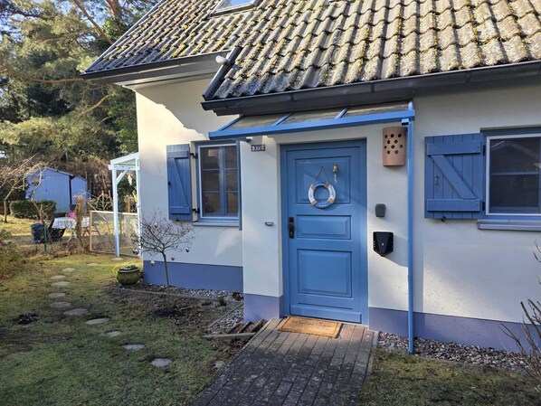 Una casa con puerta azul, un pequeño porche y techo de tejas.