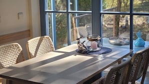 Comedor con sillas de mimbre, una mesa y vistas amplias a través de grandes ventanales.