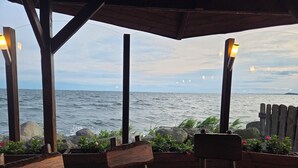 Un área de estar al aire libre con madera y vistas al mar, con un banco y una mesa.