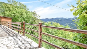 Ein Steinweg führt zu einem Holzzaun mit Blick auf ein üppiges Tal.