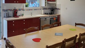 Une cuisine compacte avec des meubles rouges, une fenêtre offrant une belle vue, une table à manger avec des chaises et un petit four.