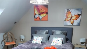 Une chambre à coucher avec un grand lit, deux tables de chevet, une chaise et deux lampes fixées au mur.