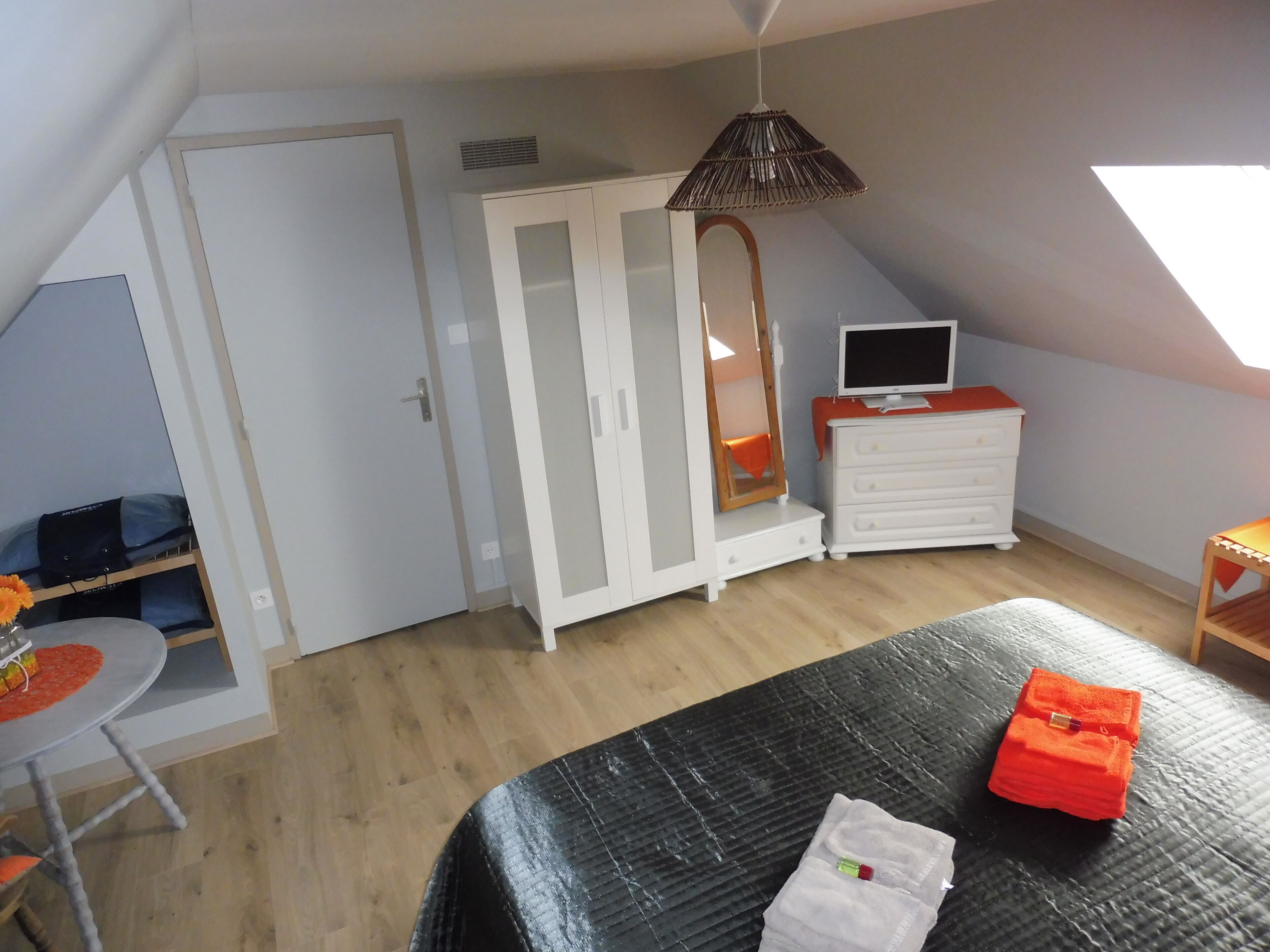 A bedroom with a bed, a dresser, a TV, a wardrobe, and a desk with a chair.