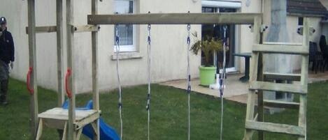 A house with a sloped roof, a swing set, a slide, and a ladder.
