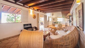 Amplia sala de estar con techos altos de madera, mobiliario de mimbre y televisor.