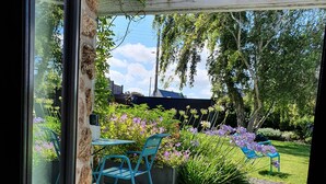 A view through a glass door of a patio area with a wooden deck, a blue chair, and a table.