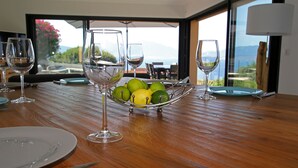 Een eettafel met een fruitschaal, wijnglazen en borden, met uitzicht op een prachtig landschap.