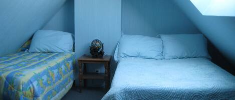 A room with two beds, a small table with a globe, and a skylight.