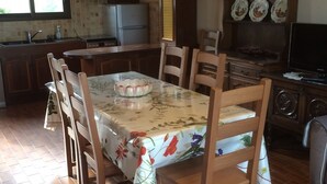 Una cocina con una mesa de madera, una araña y un ventanal.