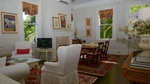 Una sala de estar con chimenea, televisor, una mesa de comedor con sillas y una estantería.