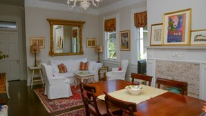 Una sala de estar tradicional con chimenea, muebles blancos y un espejo grande.