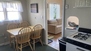 A compact kitchen with a dining area, a sofa, and a view into another room. - Cozy Cottage- 3 blocks from Main St., Walden, CO (Walden)