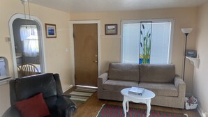 A living room with a sofa, a chair, a small table, a window with blinds, a door, and a ceiling fan. - Cozy Cottage- 3 blocks from Main St., Walden, CO (Walden)