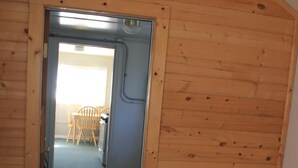 A bedroom with a bed, a wooden door leading to a dining area, and a small rug on the floor. - Cozy Cottage- 3 blocks from Main St., Walden, CO (Walden)