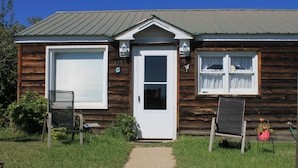 A wooden cabin with a white garage door, a front door, and a window with curtains. - Cozy Cottage- 3 blocks from Main St., Walden, CO (Walden)