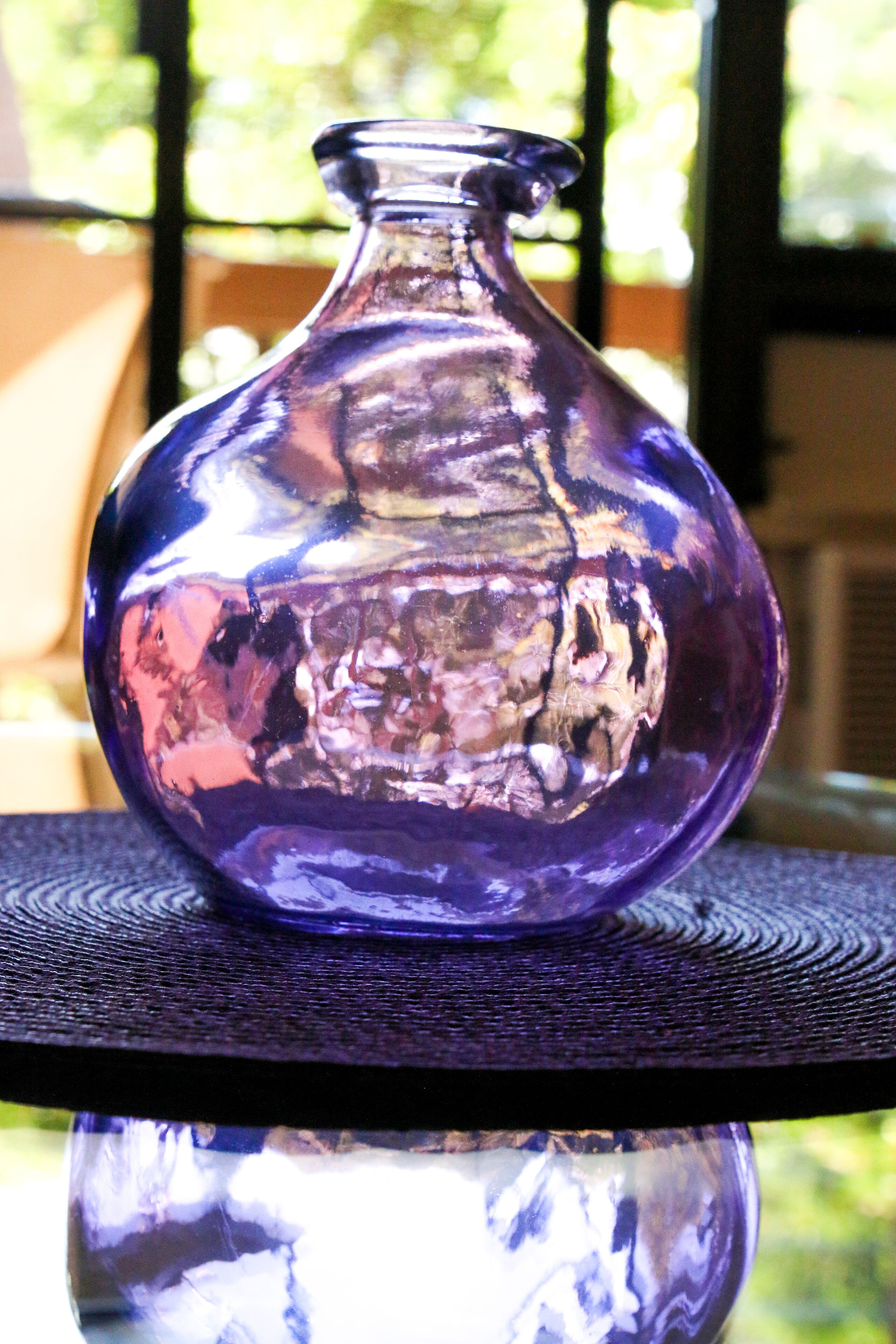 Un vase en verre violet posé sur une table à surface texturée.