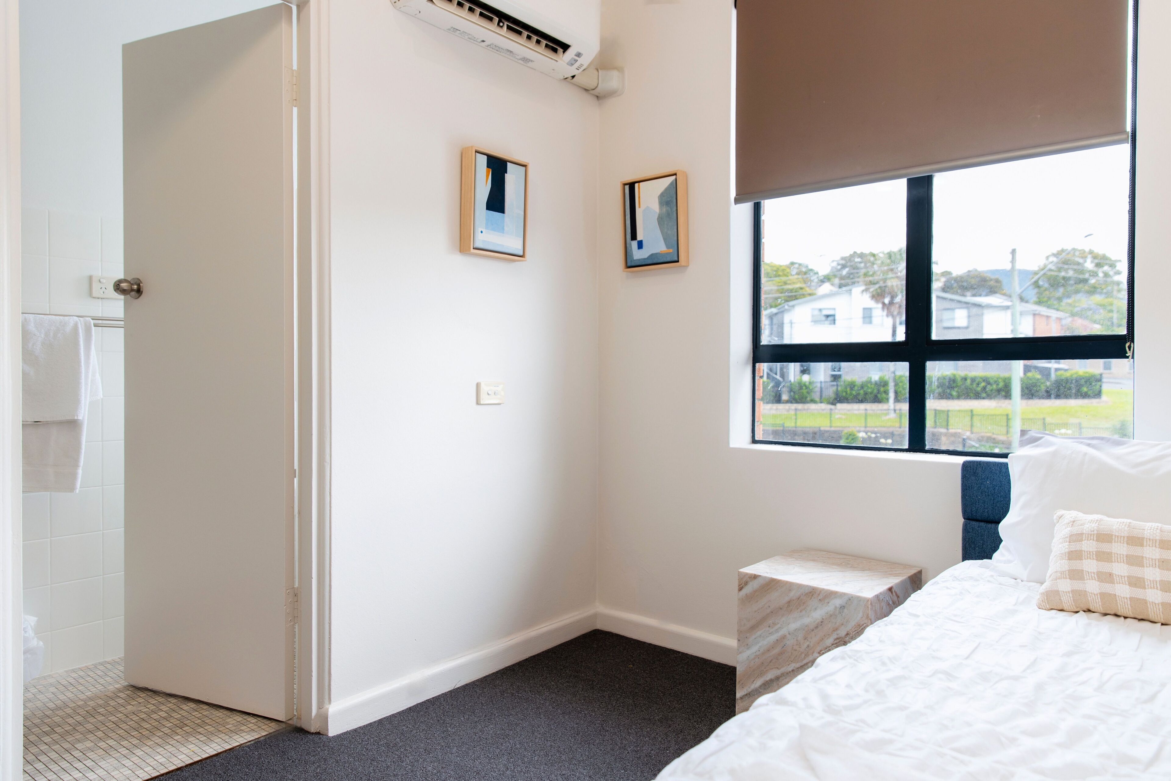 Un dormitorio con cama, ventana y dos cuadros en la pared.