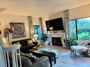 A modern living room with a fireplace, a flat-screen TV, and large windows. - 4 Bdrm Private Jungle House, minutes to all, patios, fire pit,  parking, trees! (San Diego)