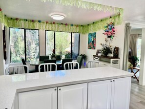 Une cuisine avec des meubles blancs, un îlot central et un coin repas avec des chaises.