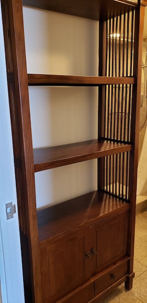 Une étagère en bois composée de trois étagères et d’un meuble bas, dotée de poignées en métal et d’une serrure.
