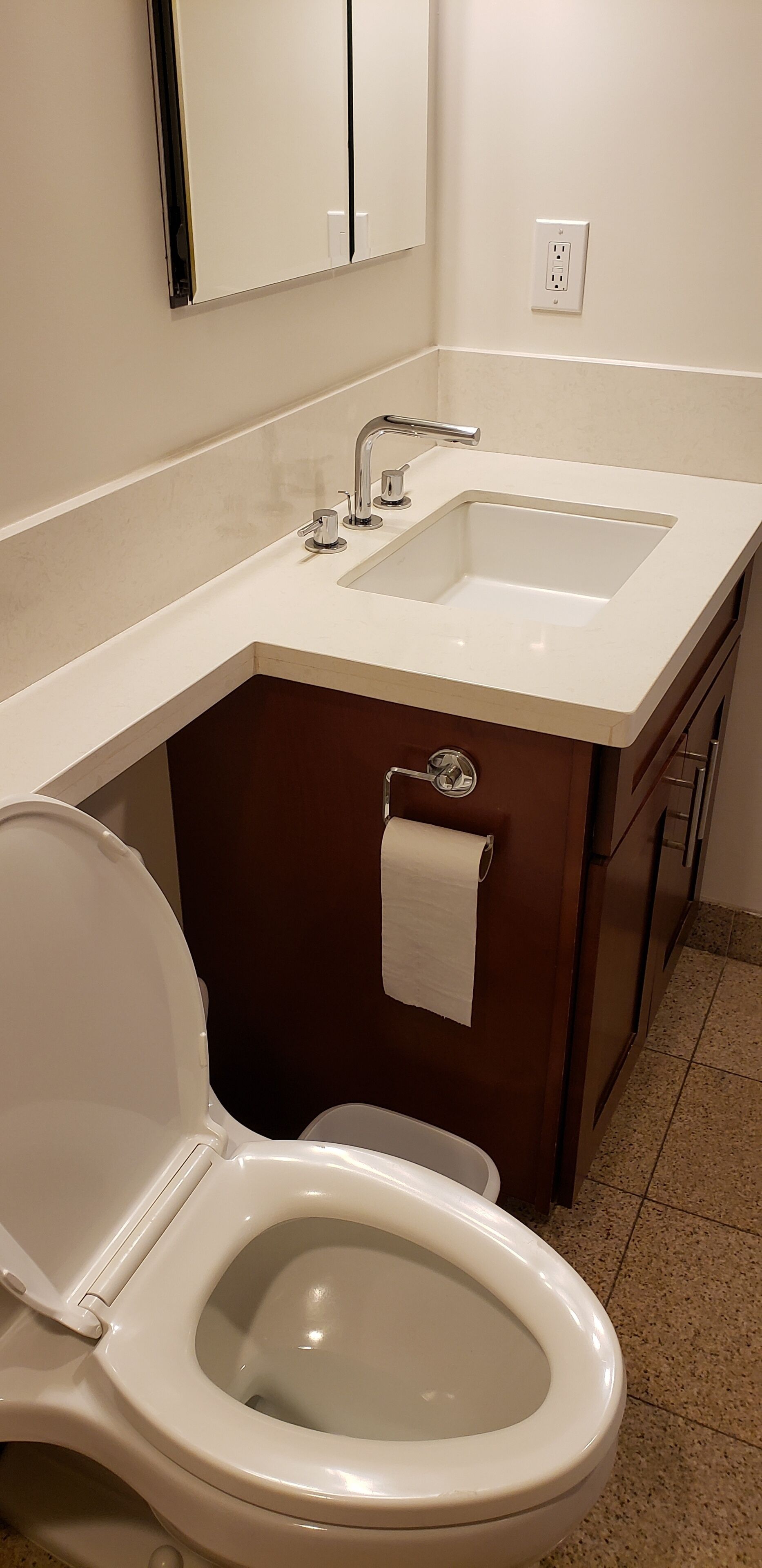 Een badkamer met toilet, wastafel en spiegel.