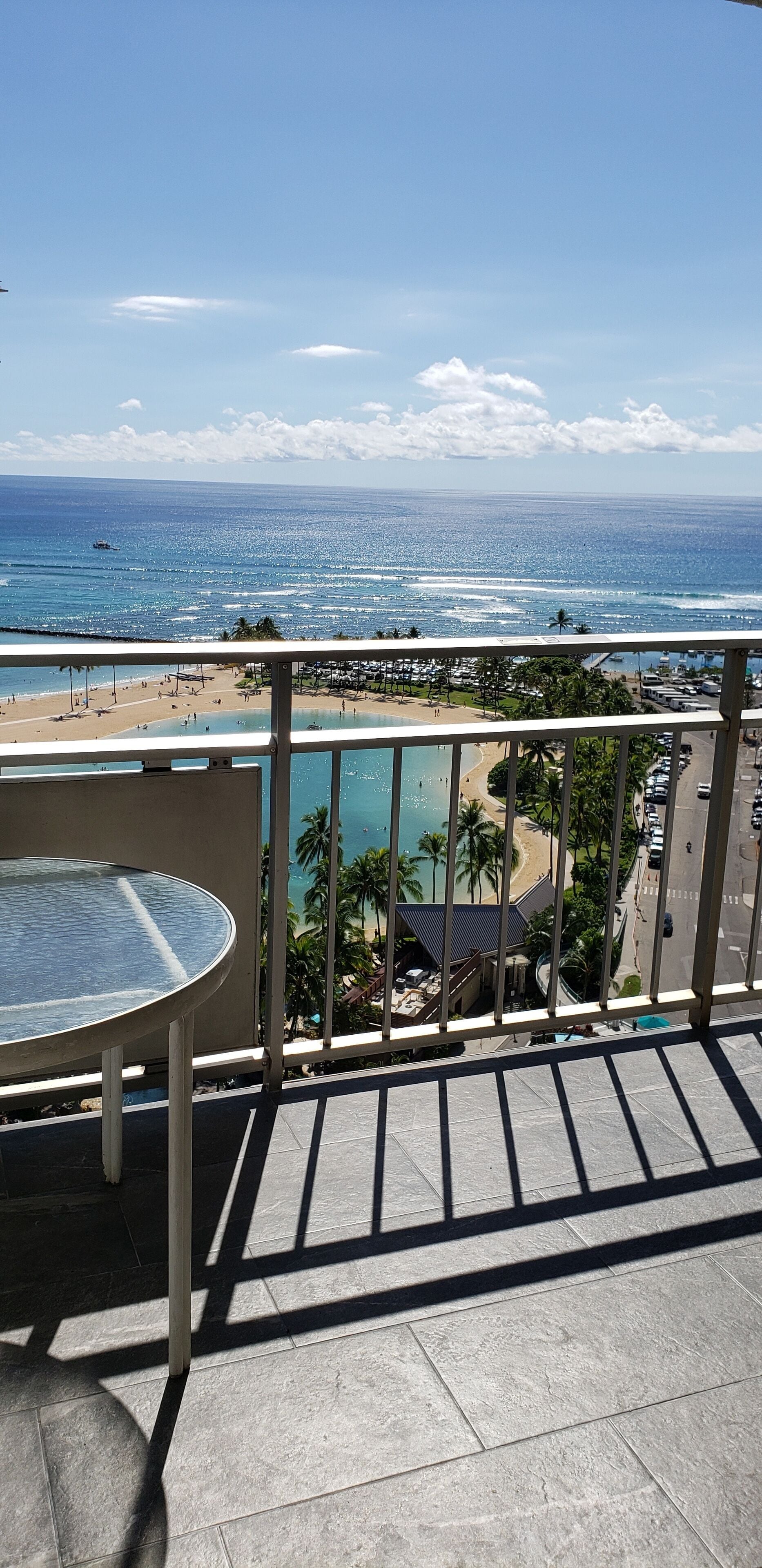 A balcony with a view of the ocean, beach, and resort area.