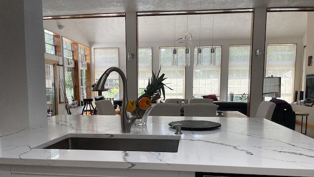 Una cocina moderna con encimera de mármol, electrodomésticos de acero inoxidable y ventanas amplias que dejan entrar luz natural.