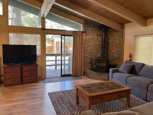 Una sala de estar con televisor, chimenea de piedra, sofá y mesa de centro de madera.