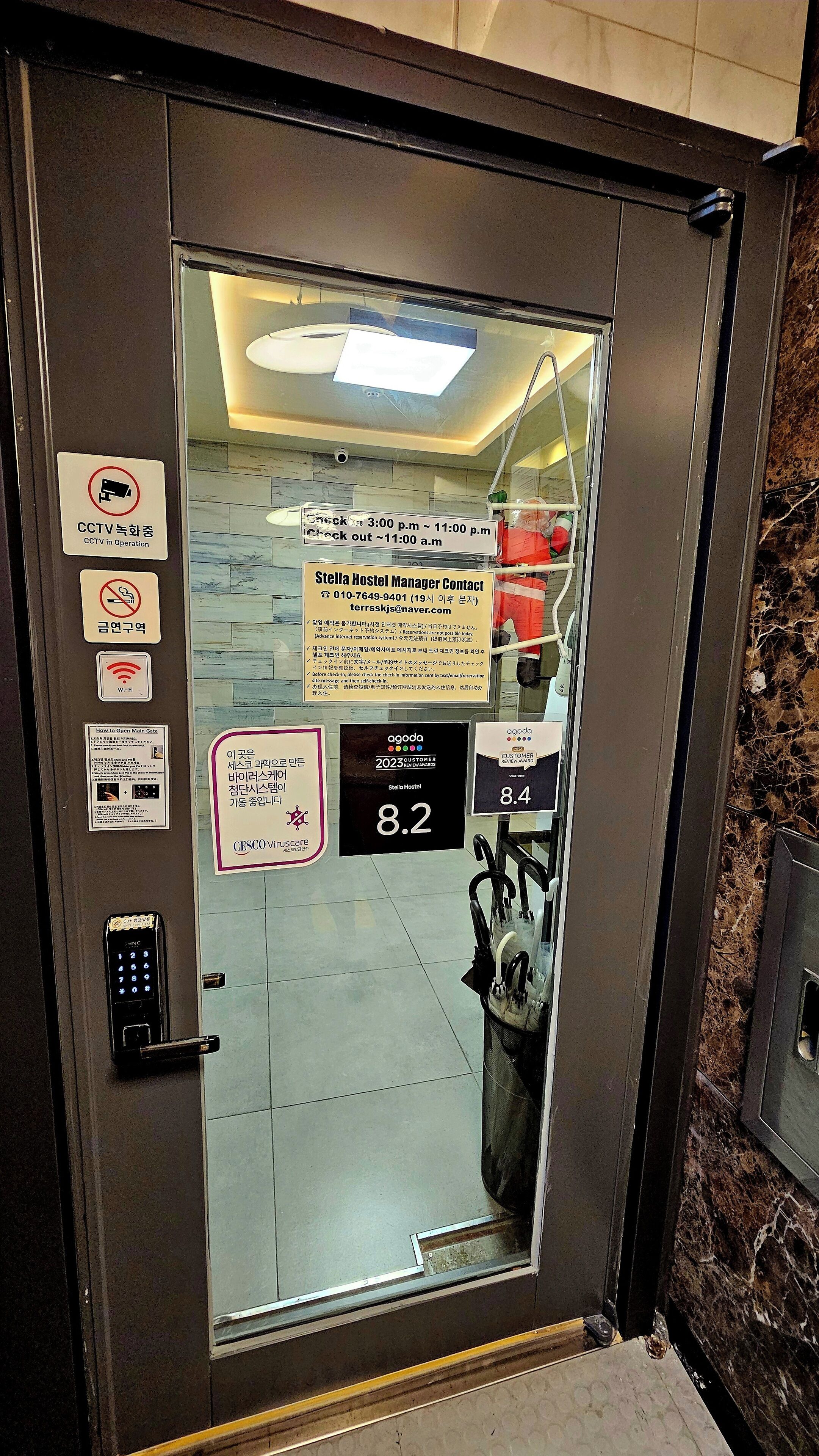 An elevator door with a digital display showing the floor number 8.2, a contact number, and a sign indicating CCTV operation.