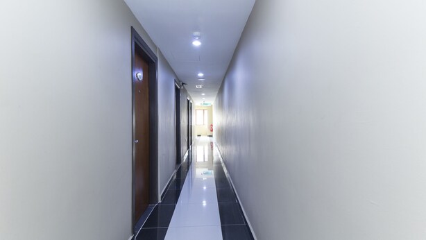 A corridor with a reflective floor, doors on both sides, and recessed lighting. - Hotel Raja Bot (Kuala Lumpur)