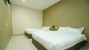 A hotel room with two single beds, a small table with a vase of flowers, and a plain wall with a light switch. - Hotel Raja Bot (Kuala Lumpur)