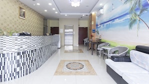 A hotel lobby with a reception desk, seating area, and a mural of a beach scene. - Hotel Raja Bot (Kuala Lumpur)