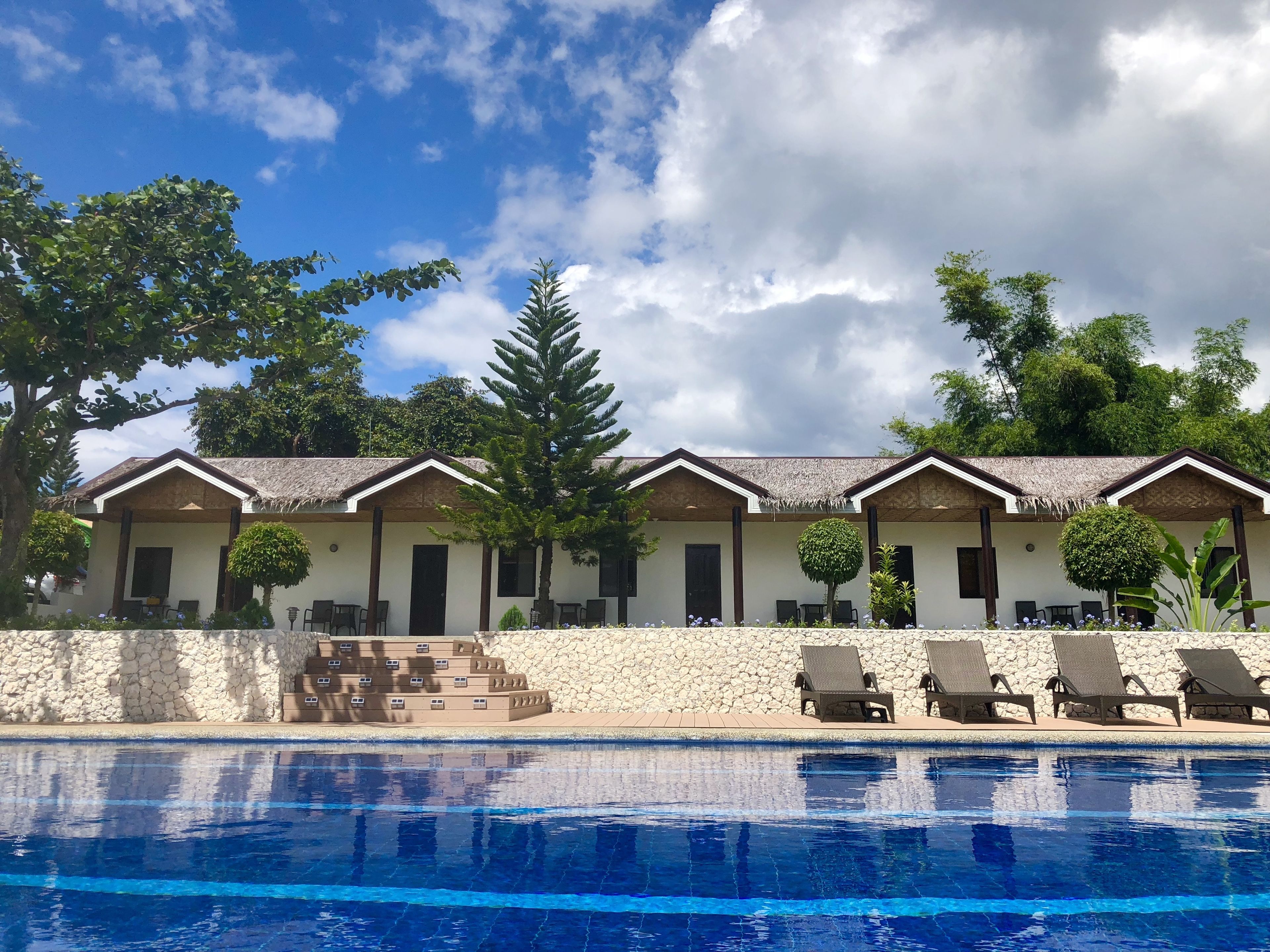 A hotel with multiple rooms, a swimming pool, and a thatched-roof structure.