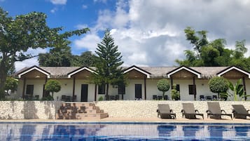 A hotel with multiple rooms, a swimming pool, and a thatched-roof structure.