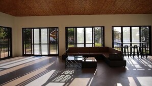Een ruime kamer met grote ramen, een houten plafond en een moderne zithoek.
