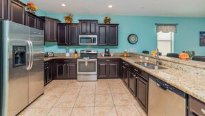 A kitchen with dark cabinets, a stainless steel refrigerator, a microwave, and a double oven. - Shv1192ha - 8 Bedroom Villa In The Retreat at Champions Gate, Sleeps Up To 20, Just 9 Miles To Disney (Davenport)