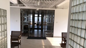A spacious corridor with tiled flooring, glass block walls, and a ceiling with exposed pipes. - Hedges Court Residencies Town Hall-2 Room 3 Bed Apartment (Colombo)