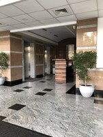 Un vestíbulo moderno con piso de mármol, mostrador de recepción y plantas en macetas.