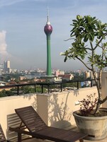 Un balcón con vistas a un paisaje urbano, incluyendo una torre distintiva.