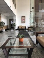 Un hall con una mesa de centro de vidrio, zona de estar y plantas en macetas.
