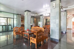 A lobby with a reception desk, wooden furniture, and a staircase.