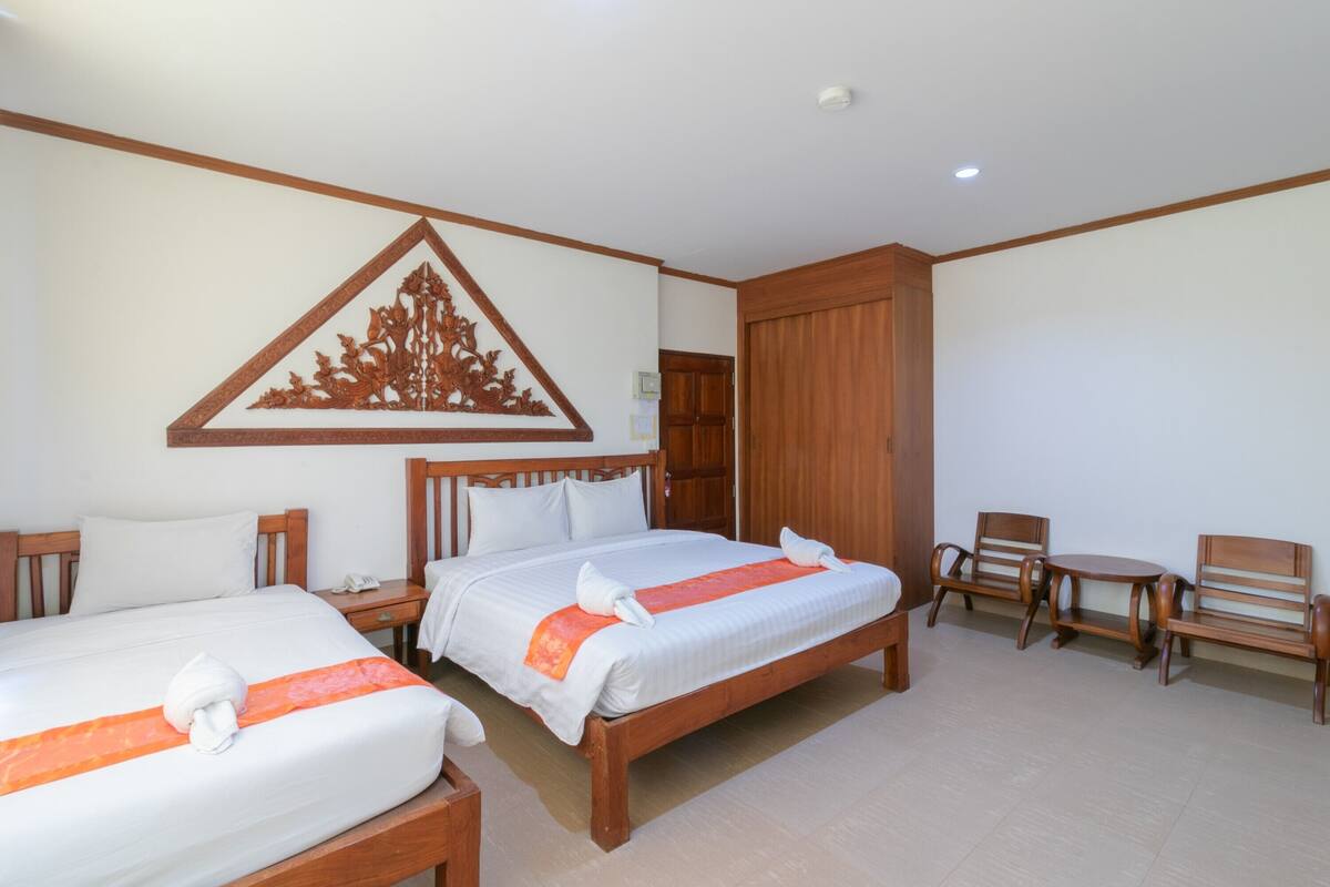 A hotel room with two beds, wooden furniture, and a decorative wall piece.
