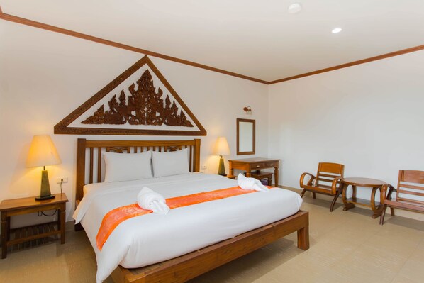A hotel room with a large bed, two bedside tables with lamps, a wooden chair, and a small table.