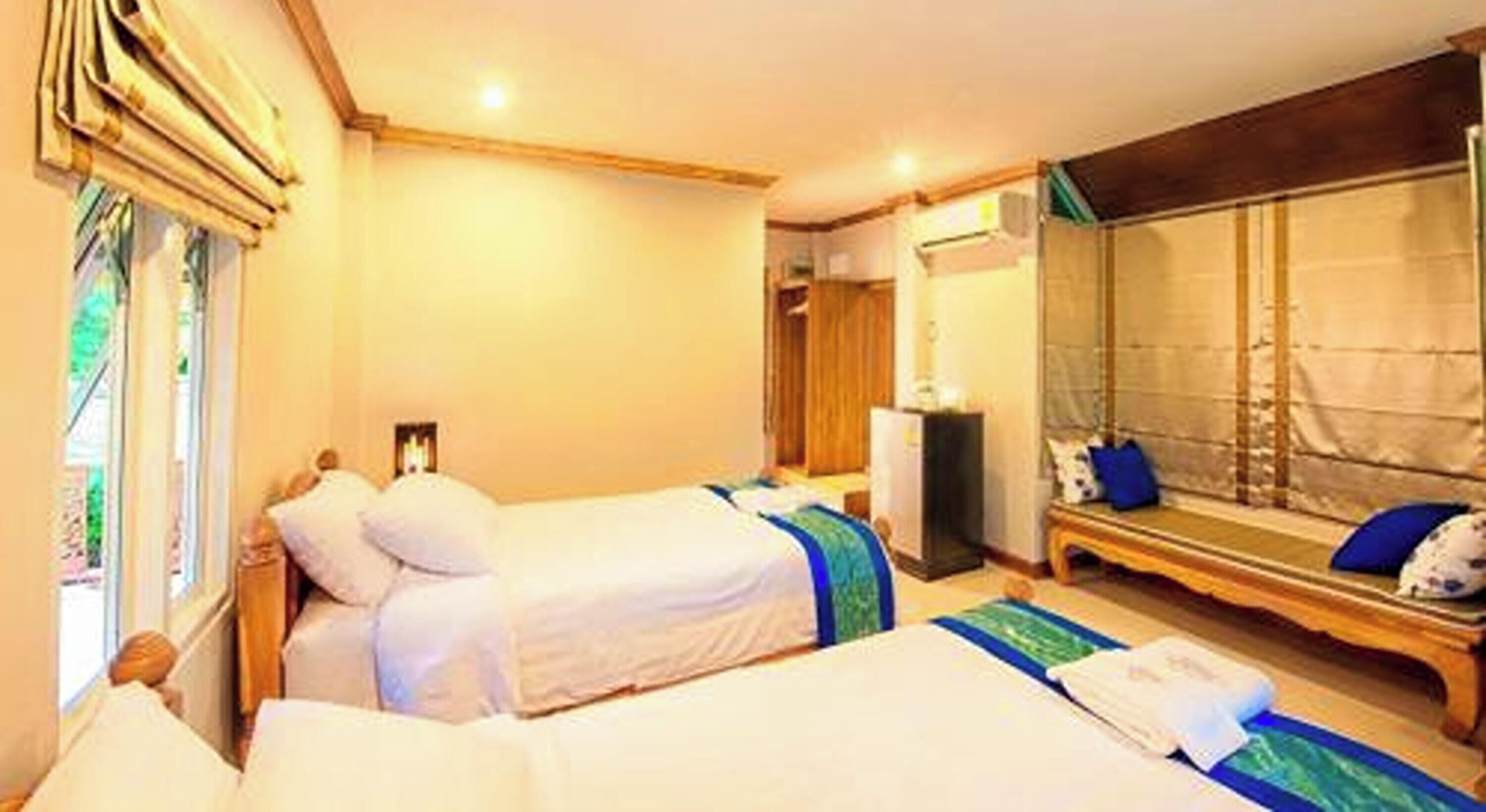 Habitación de hotel con dos camas, un espejo grande, un banco y vistas al exterior.